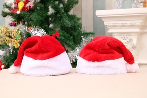 Close-up of plush red and white Christmas hats on a table with a festive fireplace background