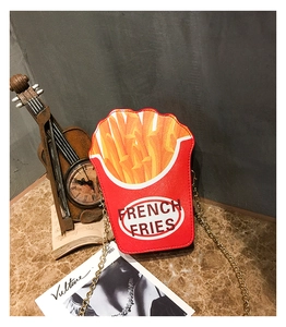 Detail of French fries shaped crossbody bag with gold chain on marble surface