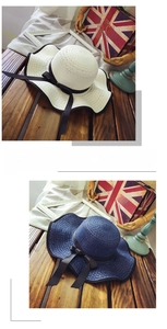 Detail of wide brim straw hats in beige and navy with black ribbon bow and wavy edges