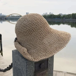 Detailed close-up of a hand-woven beige straw sun hat with a decorative side buckle