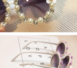 Detailed view of kids floral sunglasses with white pearls and sparkling rhinestones