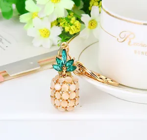 Close-up of orange opal pineapple keychain with green crystal leaves and gold clasp