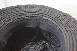 Detail view of the black raffia hat interior featuring a woven texture and adjustable sweatband