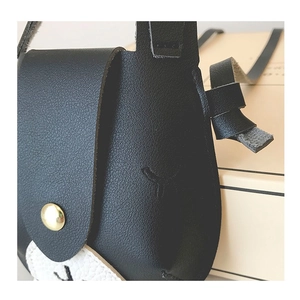 Detail of black and white litchi grain leather texture and gold metal buckle on kids bag
