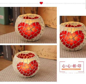 Detail of handmade mosaic glass candle holder with glowing red heart and warm light