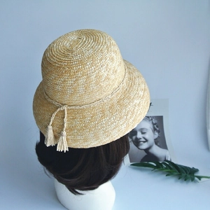 Detail view of woven straw bucket hat with tassel drawstring on a mannequin head