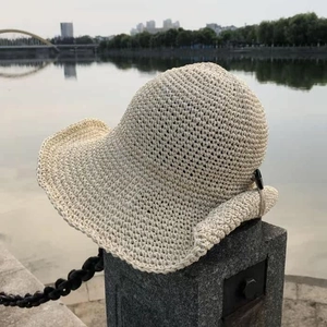 Detailed close-up of ivory crochet sun hat texture with elegant black button accent