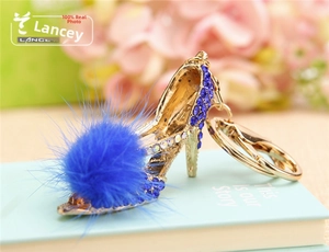Macro shot of rhinestone high heel keychain with blue fluffy ball on pastel background
