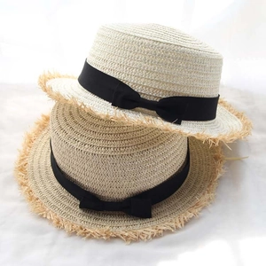 Detail of fringed straw boater hats with elegant black ribbon bows in beige and tan colors