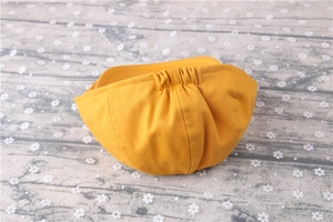 Close-up of bright yellow striped cotton beret with elastic back on wood background