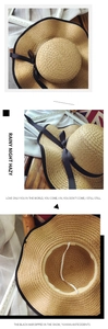 Detail view of woven straw sun hat with black ribbon bow and adjustable windproof rope