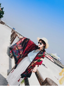 Detail of red tassel edge and Persian vine patterns on a colorful ethnic beach shawl