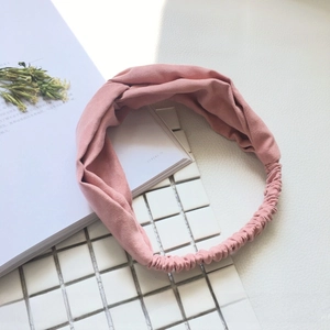 Detail of pink twisted headband in soft faux suede fabric with elastic band design