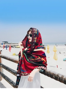 Detailed bohemian print on red ethnic style shawl scarf against beach background