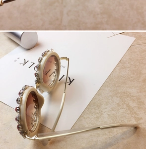 Detail of cream white oversized sunglasses with pink rhinestones and gradient lenses
