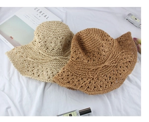 Detail of wide brim straw sun hats with hollow crochet patterns and bow accents