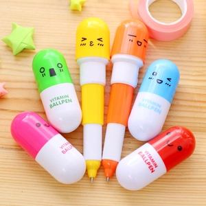 Macro view of colorful pill-shaped telescopic ballpoint pens with cute faces on wood table