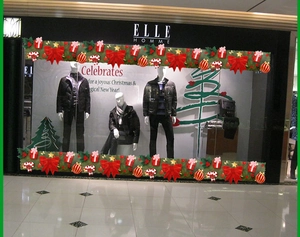 Detail of Christmas window stickers featuring green pine garlands and red bows on glass