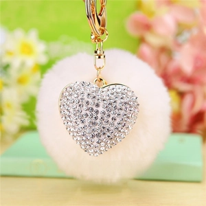 Close-up of heart-shaped rhinestone charm with soft plush pompom and gold keychain