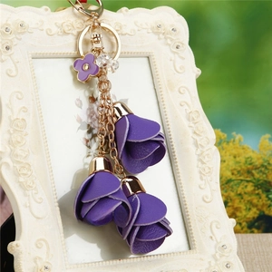 Detail of purple floral keychain with layered leather petals and gold chain on vintage frame
