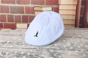 Detail of light blue striped baby beret with rabbit embroidery on vintage background