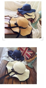 Detail of wide brim straw hats with black ribbon bows in navy, beige, and cream colors