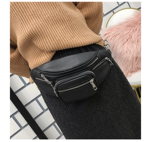 Detail of a black PU leather crossbody waist bag with multiple zippers worn by a model