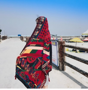 Detail shot of ethnic paisley scarf featuring colorful boho prints and red tassels