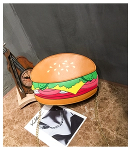 Close-up of creative hamburger-shaped crossbody bag with gold chain strap on table