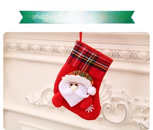 Detail of red Christmas stocking with Santa Claus 3D figure and plaid trim on fireplace