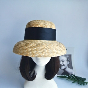 Classic straw boater hat with black grosgrain ribbon on a mannequin head, retro style