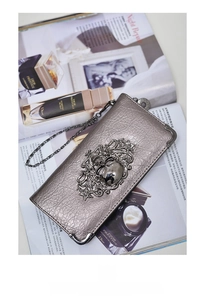 Detailed view of skull embossed long wallet with metallic hardware and chain strap