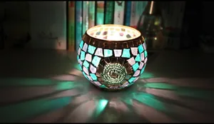 Macro shot of mosaic glass candle holder casting colorful light patterns in dark room