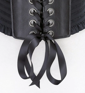 Close-up detail of black wide corset belt with metal eyelets and elegant ribbon bow.