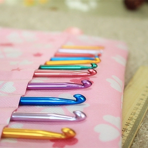 Macro view of colorful anodized aluminum crochet hooks in a floral storage case