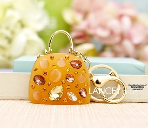Macro shot of orange purse keychain with sparkling crystals and golden hardware detail