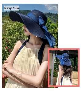 Detail of navy blue straw sun hat with a large elegant bow and wide brim for beach wear