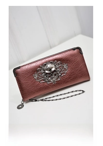 Close-up of rose gold skull wallet with ornate floral embossing and metal chain