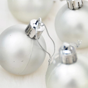 Detail of silver matte Christmas ornaments with festive hooks on white fluffy background