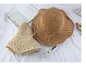 Detail of hand-woven straw hats with openwork crochet patterns and wavy brims in beige