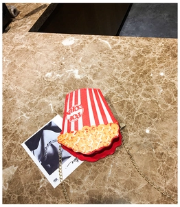 Detail view of popcorn shaped crossbody bag with red stripes and golden chain strap