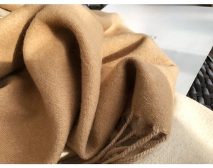 Close-up of camel cashmere-feel scarf with soft fringe details and thick texture