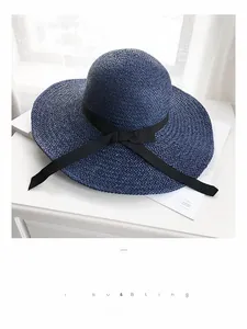 Detail of hand-woven navy straw hat featuring a wide brim and elegant black ribbon bow