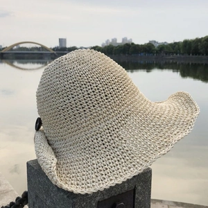 Detail of hand-crocheted cream sun hat with wide brim and elegant black button accent