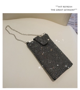 Close-up of luxury black rhinestone crossbody phone bag with silver chain on leather surface