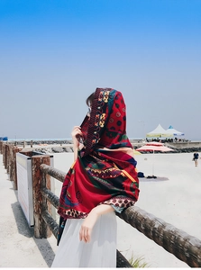 Ethnic red oversized shawl with paisley prints worn by a model at the beach