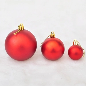 Detailed view of three matte red Christmas balls with golden caps on white faux fur