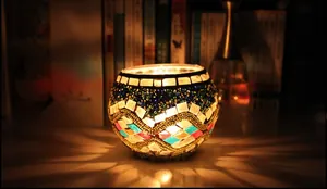 Detail of mosaic glass candle holder showing colorful fragments and warm light glow