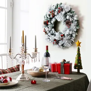 Flocked Christmas wreath with pine cones and red berries next to a mini felt tree