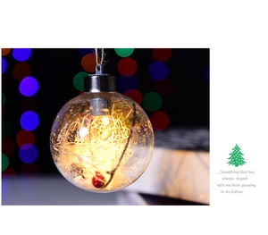 Close-up of clear 8cm LED Christmas ball with warm string lights and red berry decor